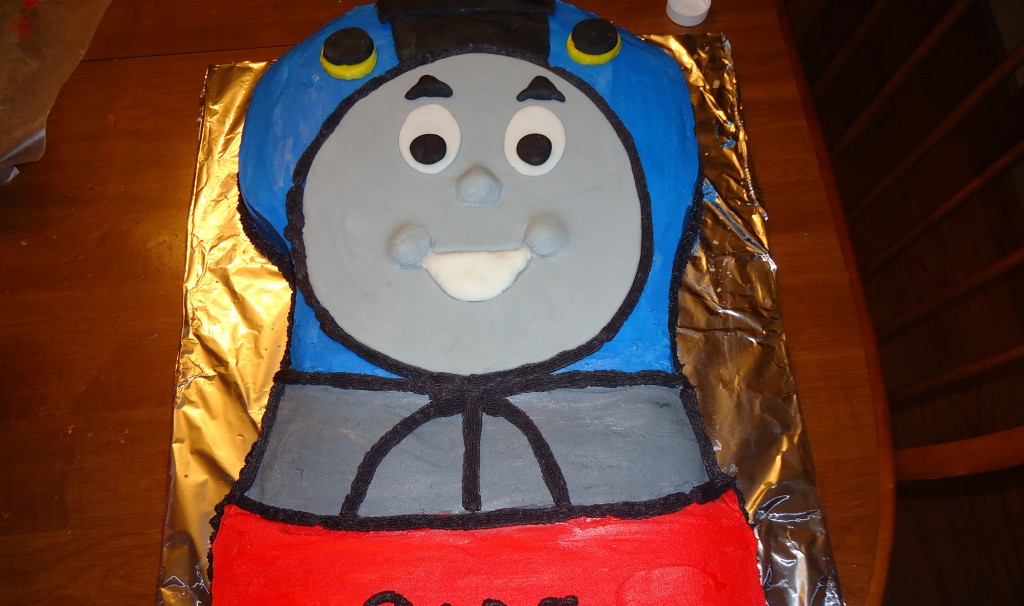 Thomas the Train birthday cake on a foil tray with smiling eyes and mouth