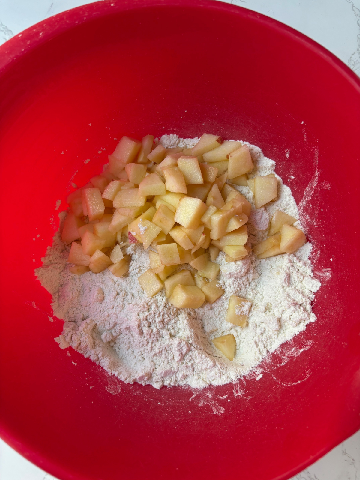 apples and flour in red bowl.
