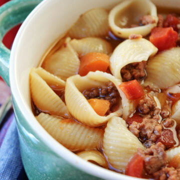 pasta shells, hamburger and tomatoes in a bowl on a colored towel