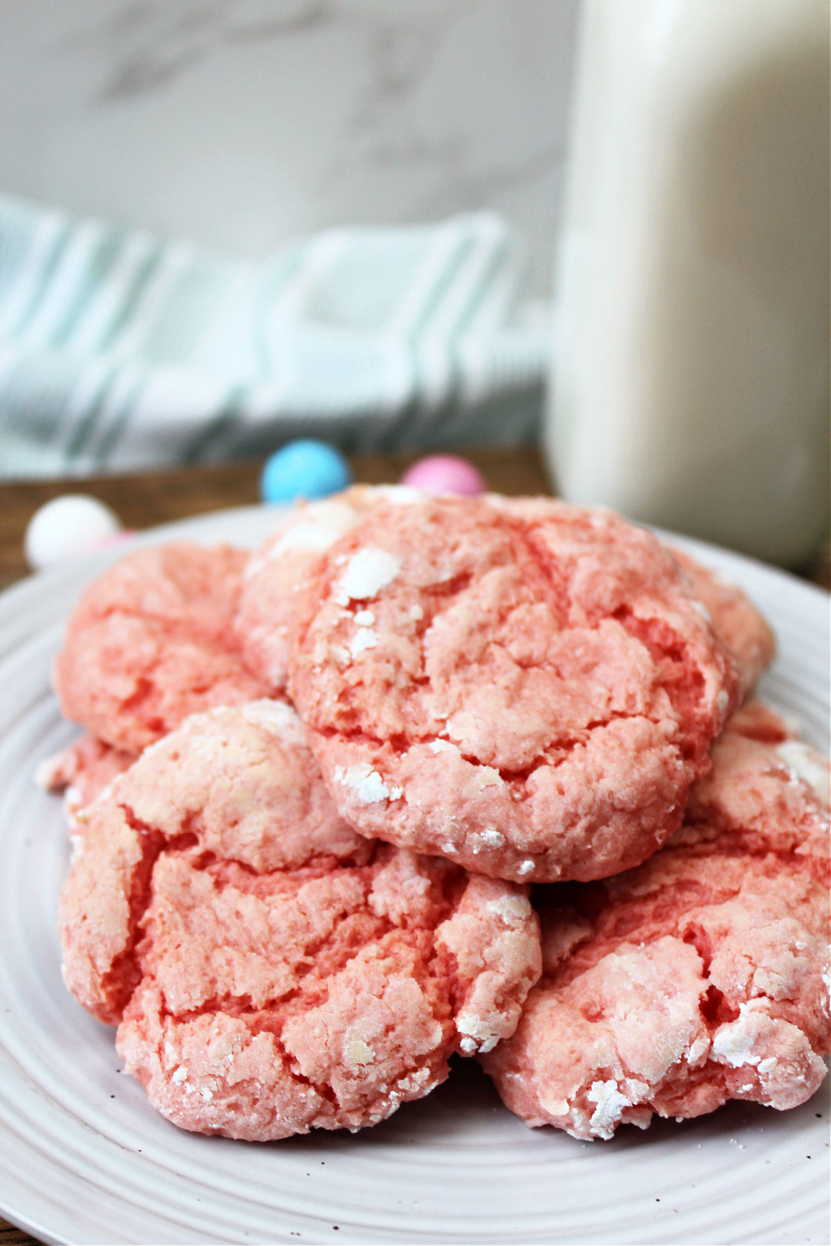 strawberry cookies on a white plate with milk behind.