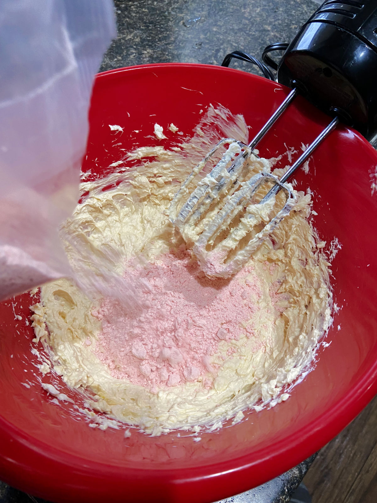 cake mix being poured into a red bowl. 