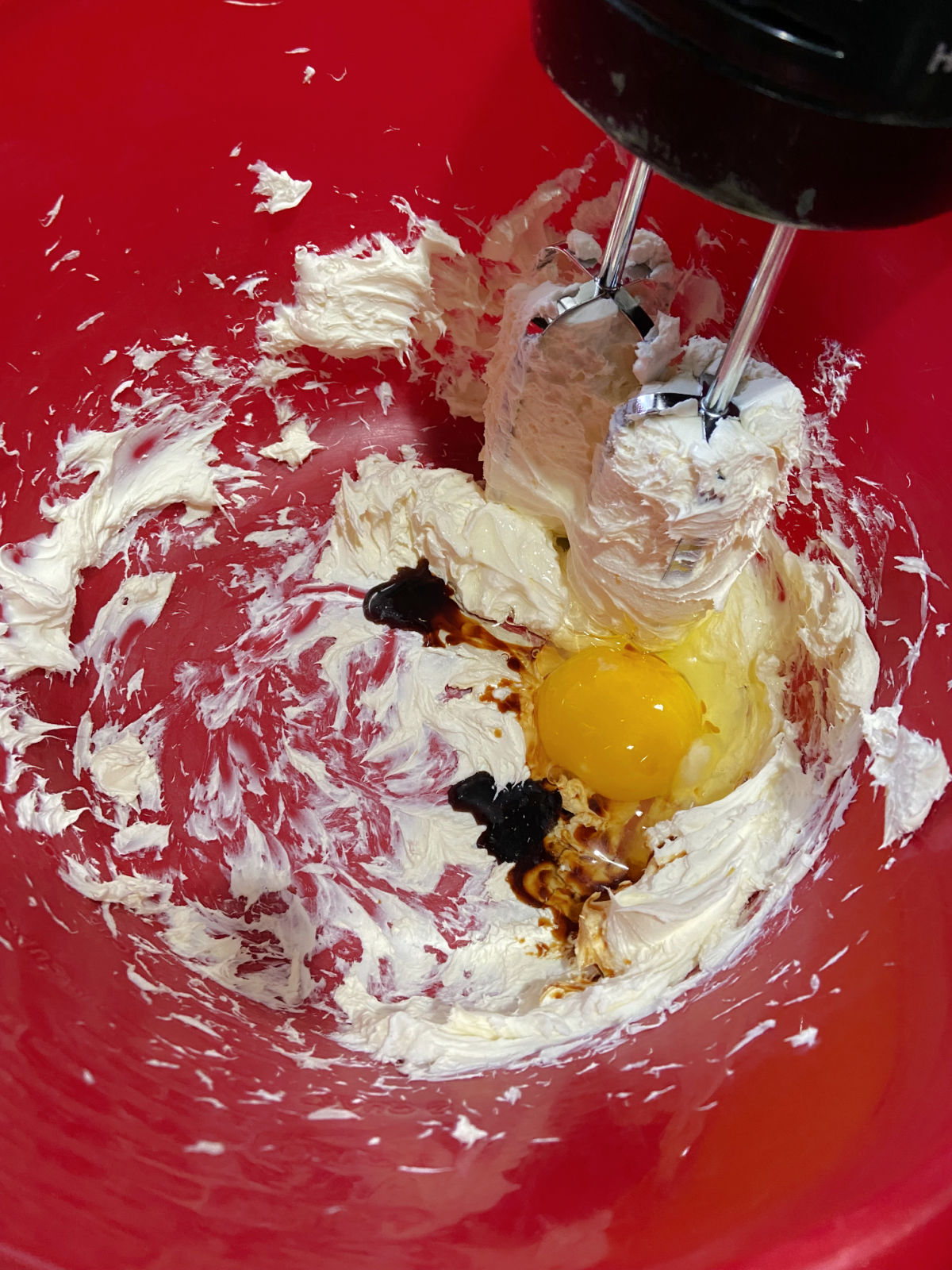 egg and butter being mixed together in a red bowl. 