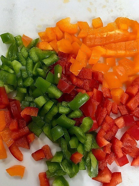 Chopped red, green and orange peppers on a cutting board