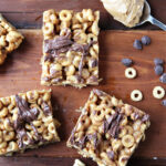 peanut butter bars with Cheerios and chocolate chips laying besides.