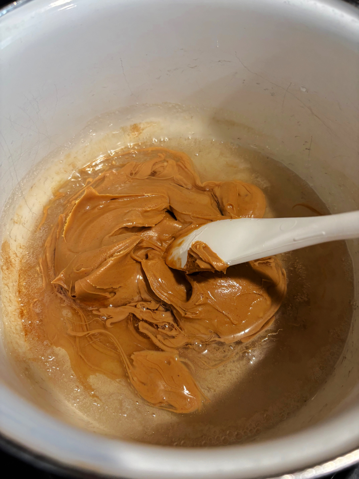 peanut butter with corn syrup in a white pot with a spoon. 