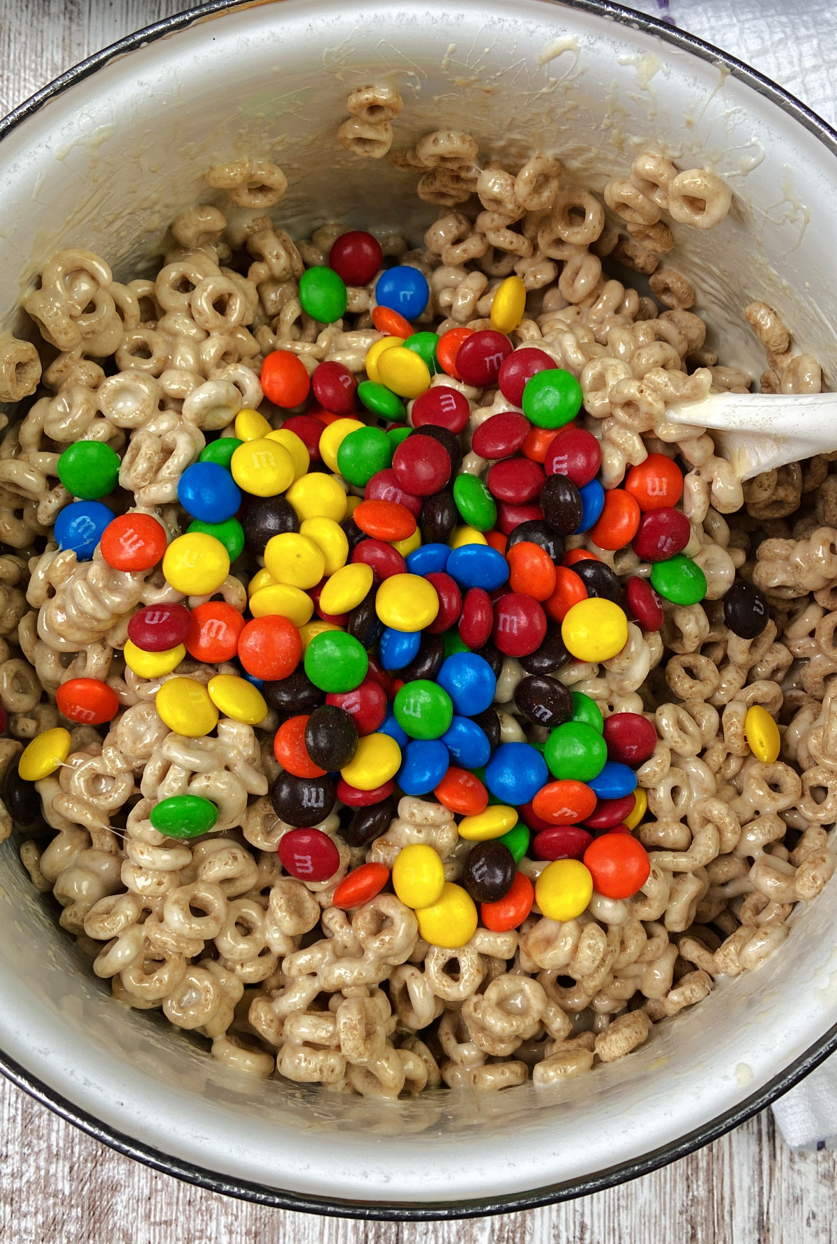 M&M's on Cheerios mixture in a white pot.