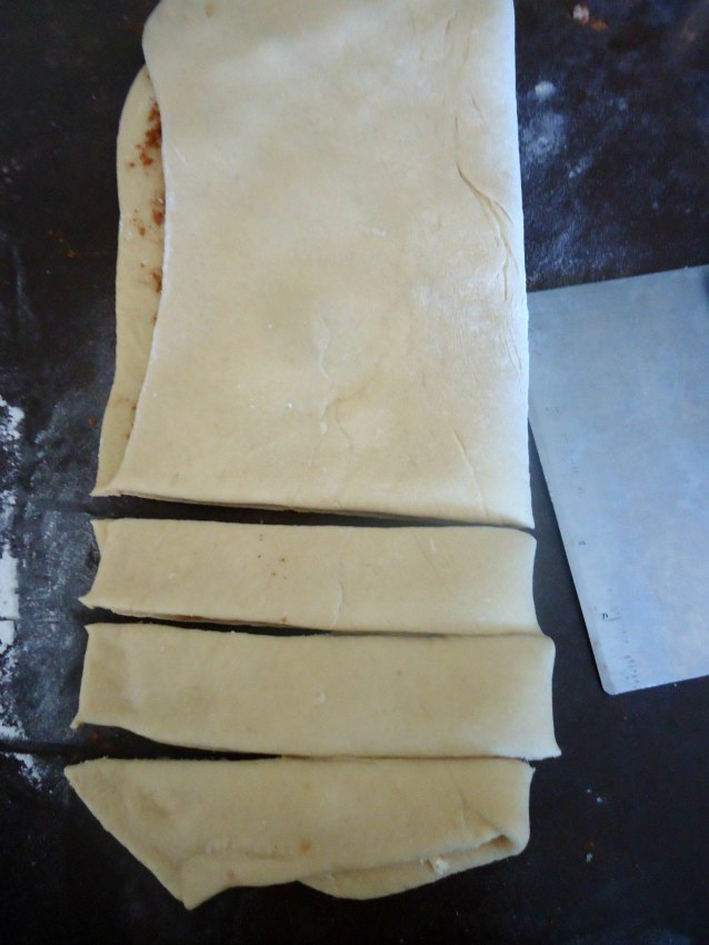 Folding over the dough for the cinnamon twists. The dough is cut into strips. 