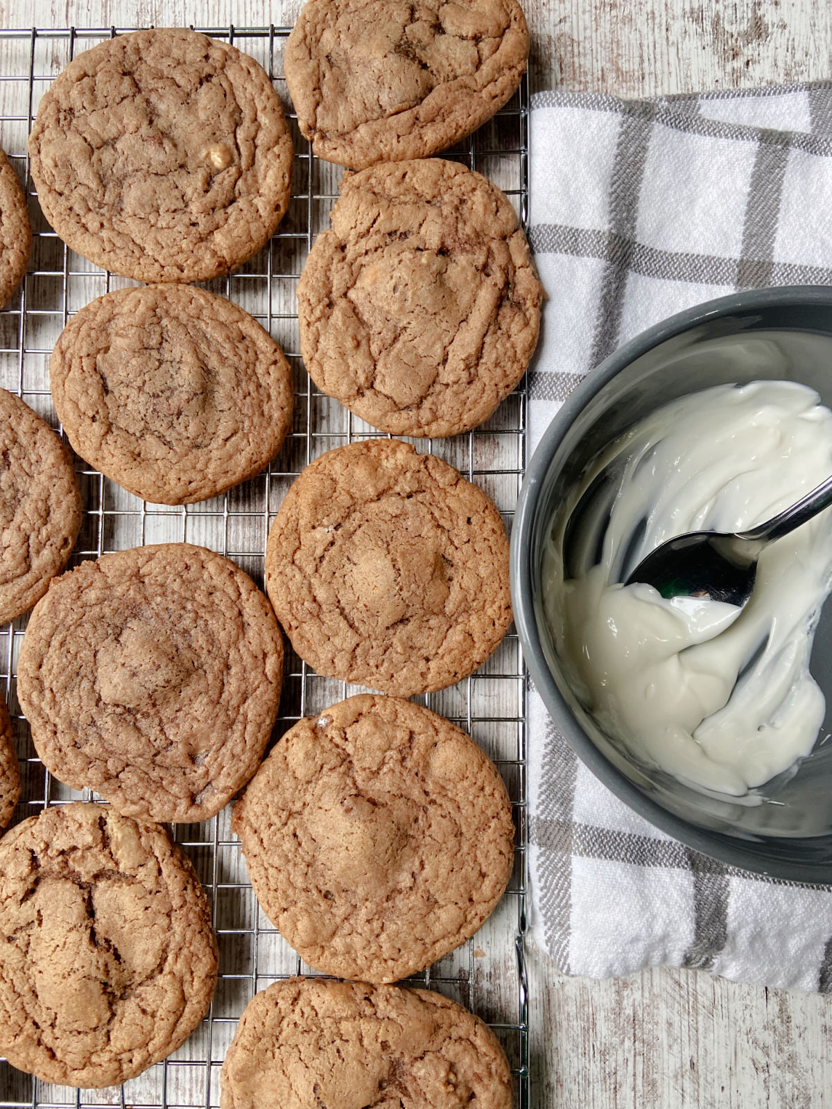 cookies on a cooling rack with almond bark in a bowl. 