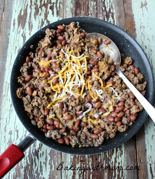 hamburger and beans in a pan with shredded cheese on top. 