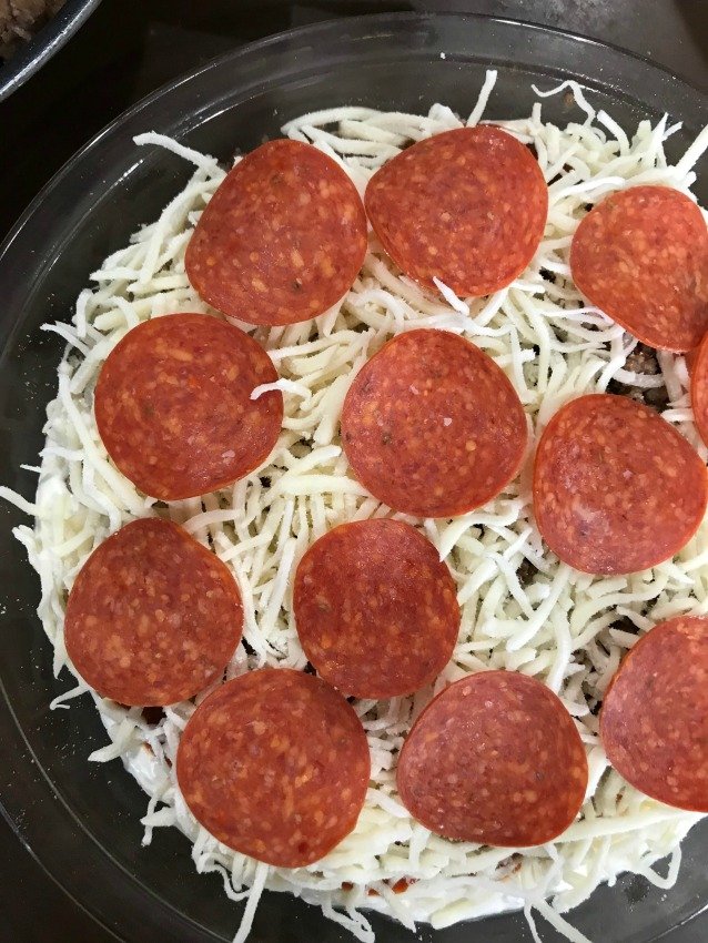 Pepperoni and cheese on top of a clear pie plate for hot pizza dip