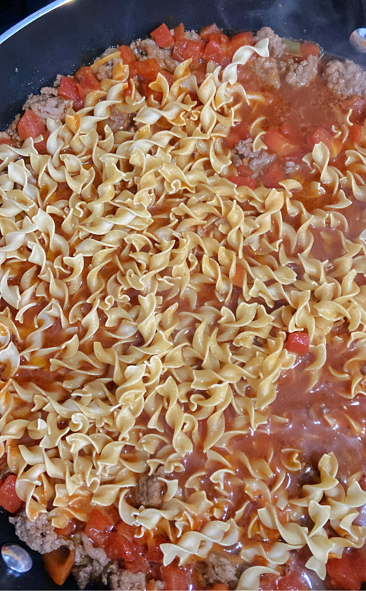 noodles on tomatoes in pan. 