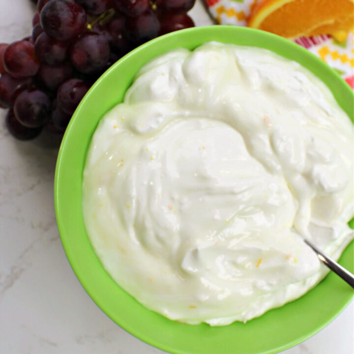 Orange fruit dip with grapes and oranges and towel besides.