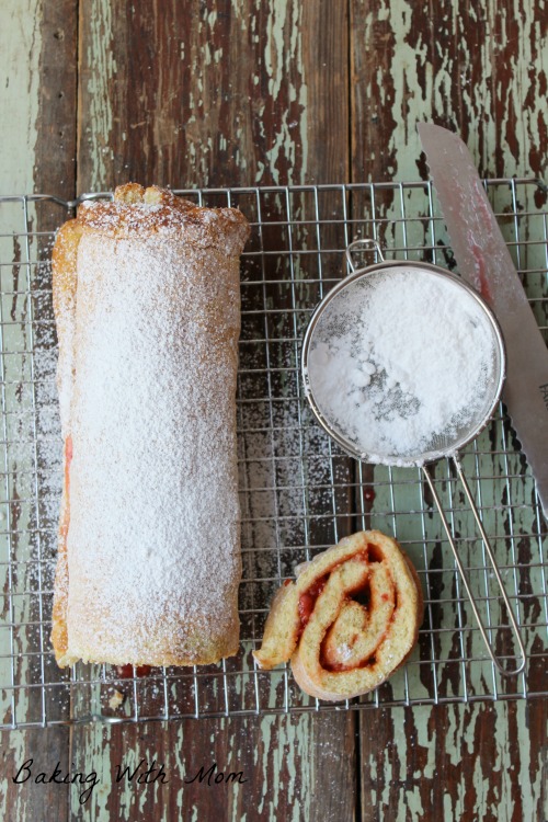 strawberry jelly roll with powdered sugar and strawberry swirl