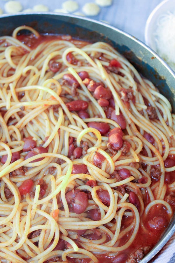 Chili and Noodles in a pot with crackers and white cheese in a bowl besides