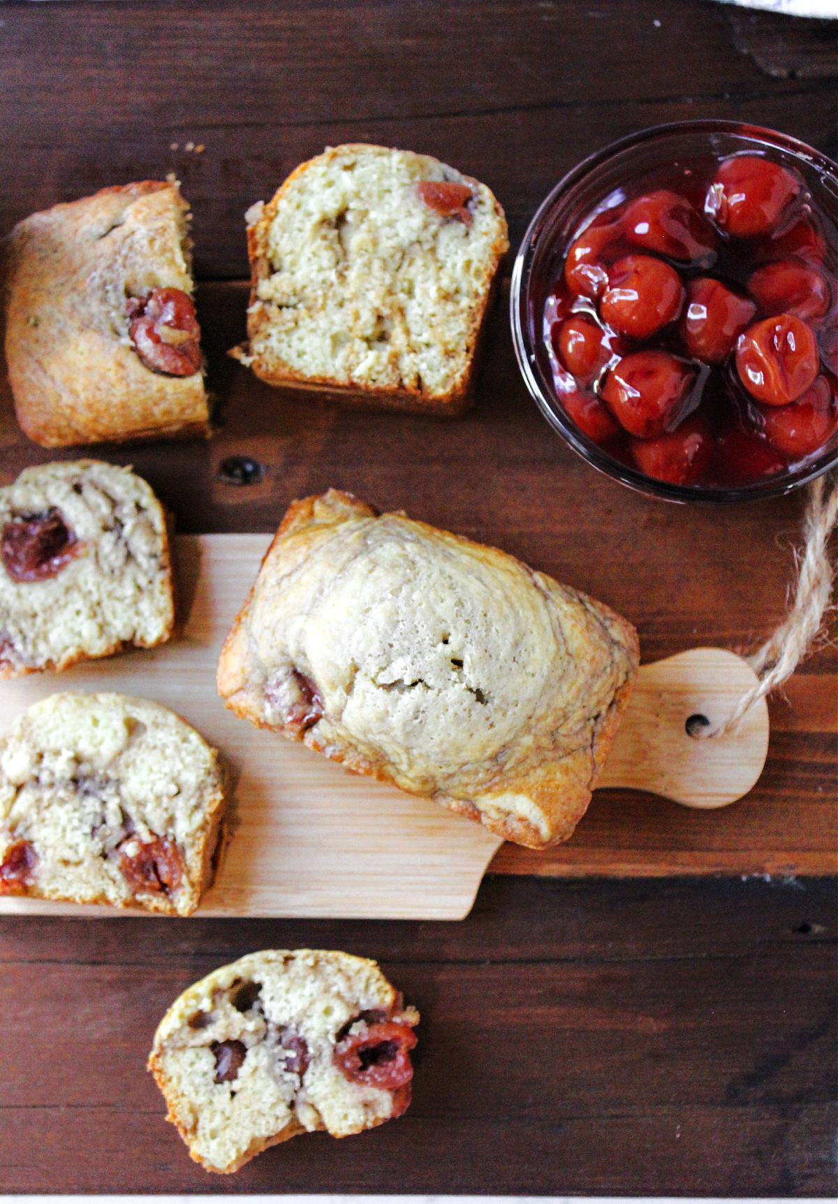 cherry bread on a brown board with cherries in a bowl. 