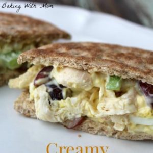 chicken salad sandwich on a white plate with grapes and celery