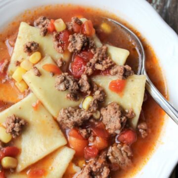 Zesty Hamburger Dumpling Soup in a white bowl with tomatoes and hamburger