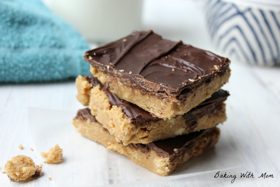 Peanut butter bars stacked with rich chocolate frosting, blue and white bowl behind