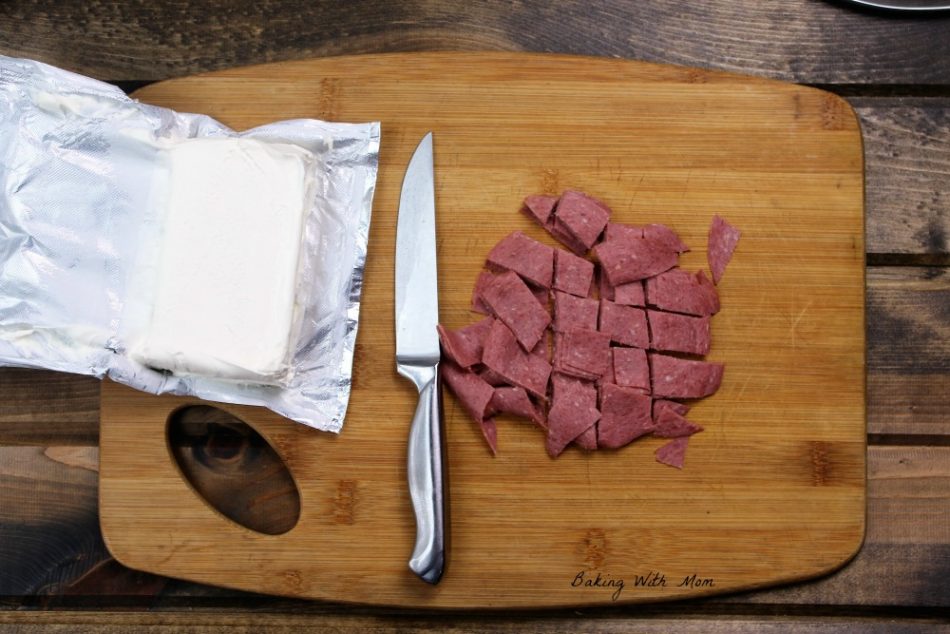 Slice corned beef on a cutting board and a block of cream cheese