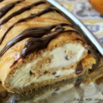 Pumpkin ice cream roll on a silver platter with chocolate drizzled on top