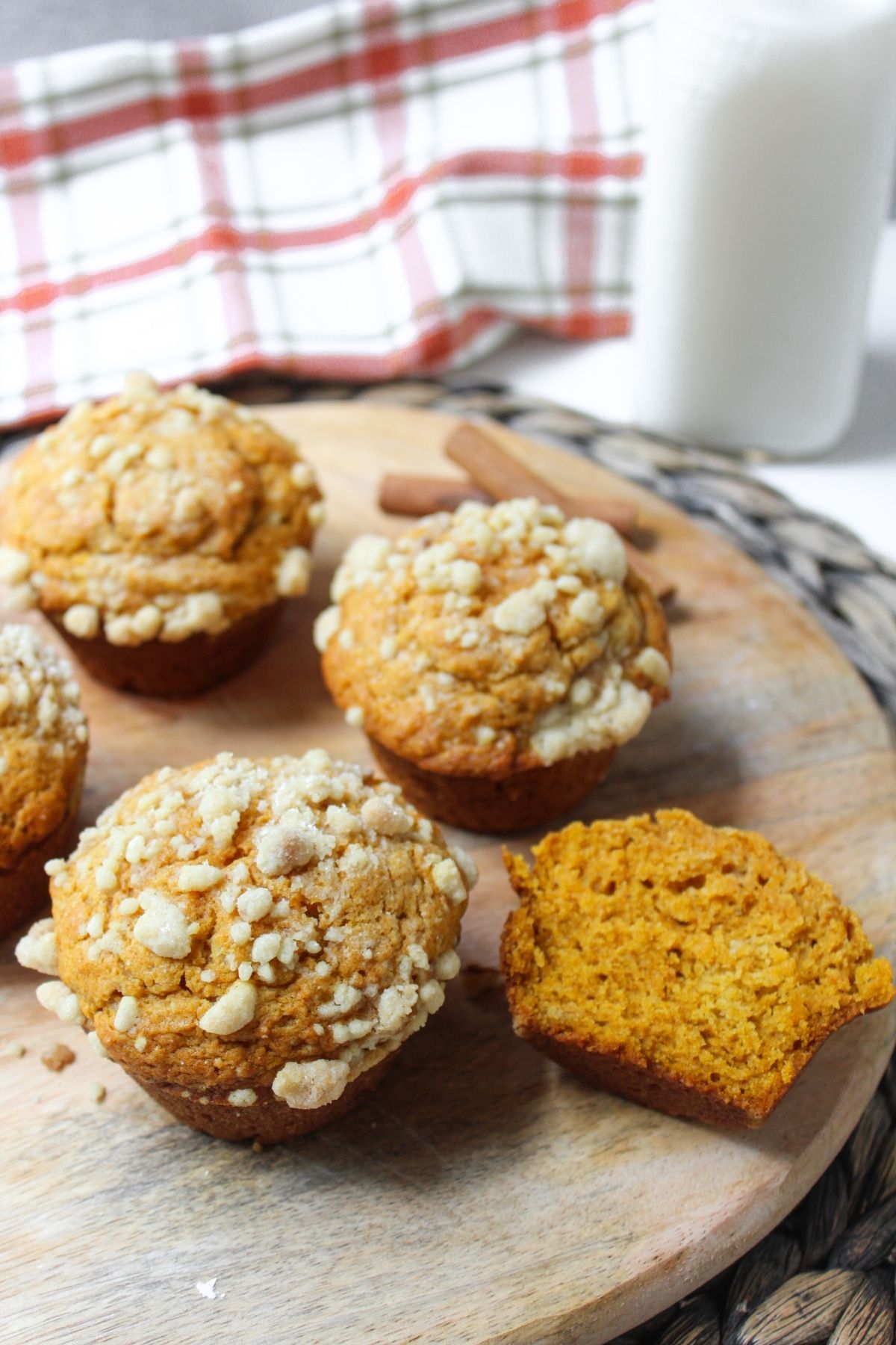Pumpkin muffins with a streusel topping on a wooden cutting board with milk behind.