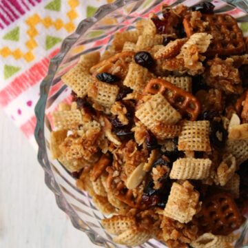 Honey Craisin Snack Mix with pretzels, rice cereal, honey and brown sugar in a clear bowl