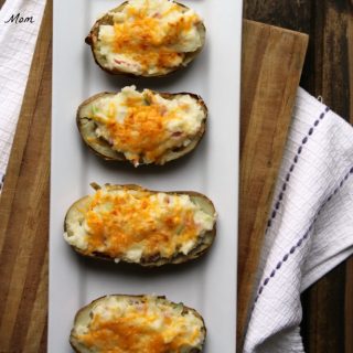 Ham Stuffed Twice Baked Potatoes with melted cheddar cheese on top on a white plate