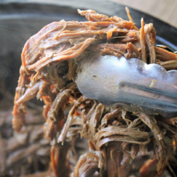 roast beef shredded held by tongs