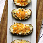 twice baked potatoes on a white platter with a towel.