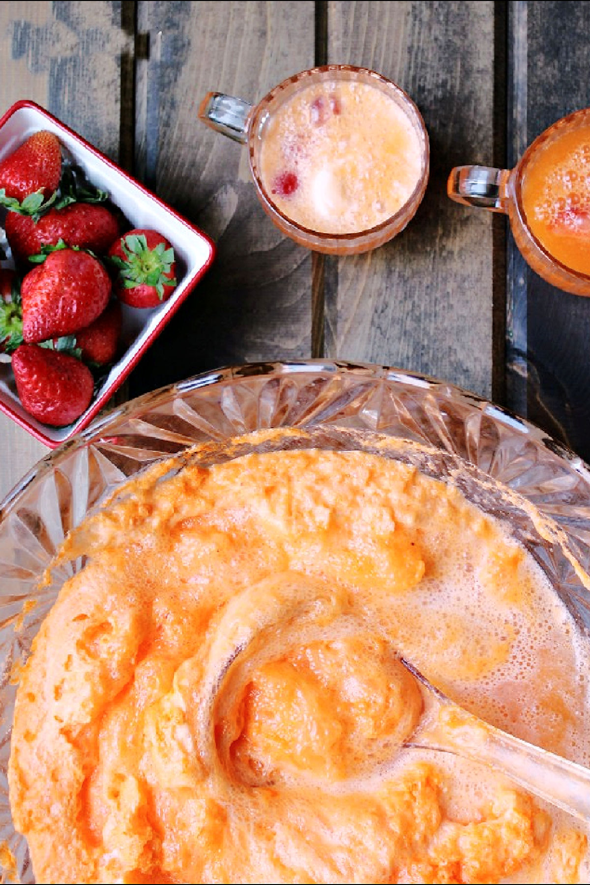 orange punch in a punch bowl with strawberries. 