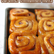 Cinnamon rolls on a pan with milk behind.