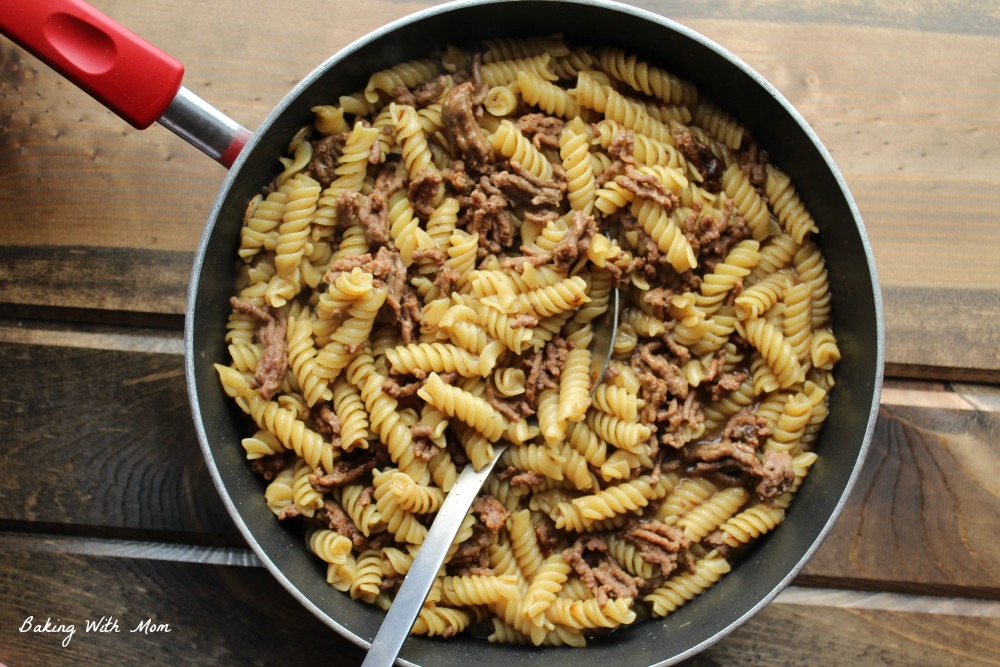 hamburger helper beef pasta in a frying pan with a silver spoon. 