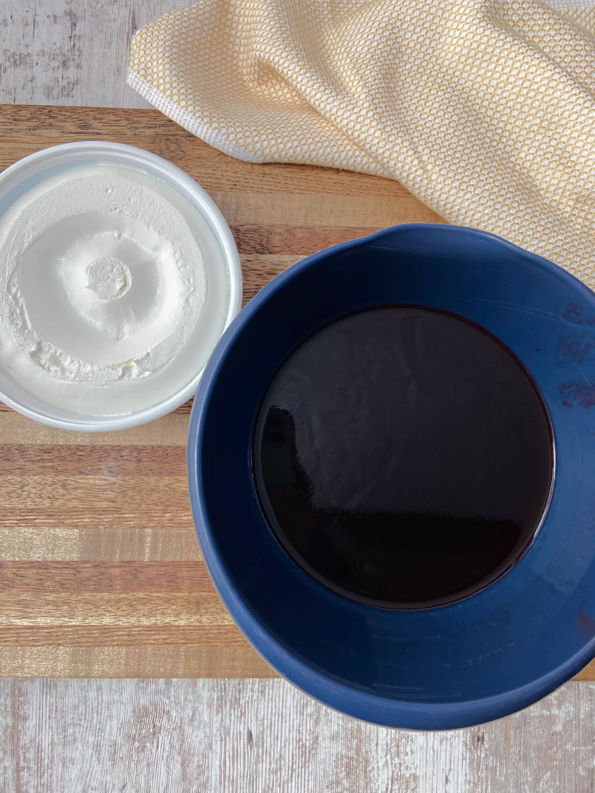 Red Jello in a blue bowl with cool whip.