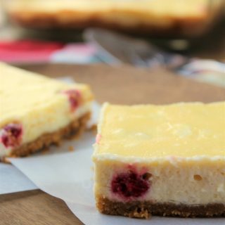 cheesecake squares slices with raspberries on waxed paper