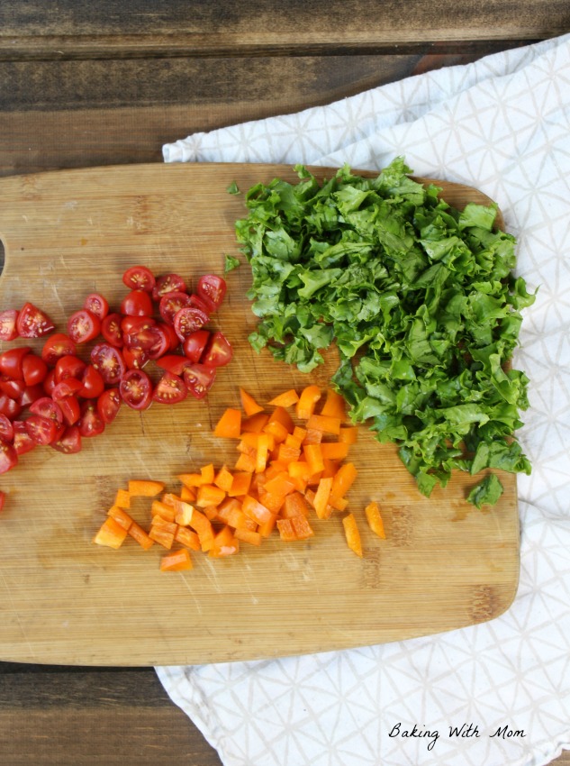 Orange peppers and tomatoes and lettuce on cutting board