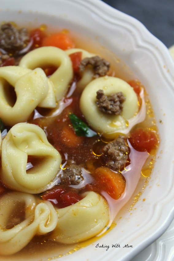 Hamburger Tortellini Soup with carrots and tomatoes in a white bowl with crackers