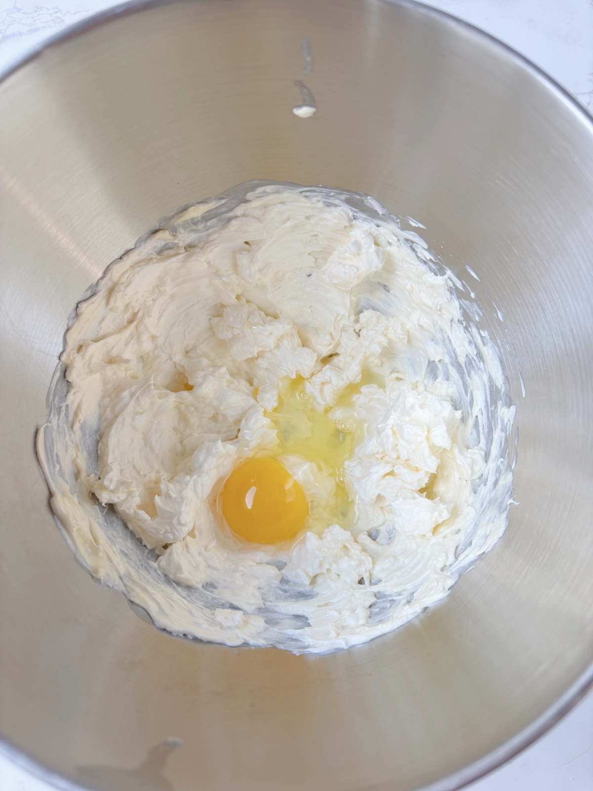egg in a silver bowl with batter.
