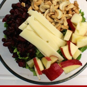 Apple Cranberry Lettuce Salad in a clear bowl with cheese, apples and cranberries