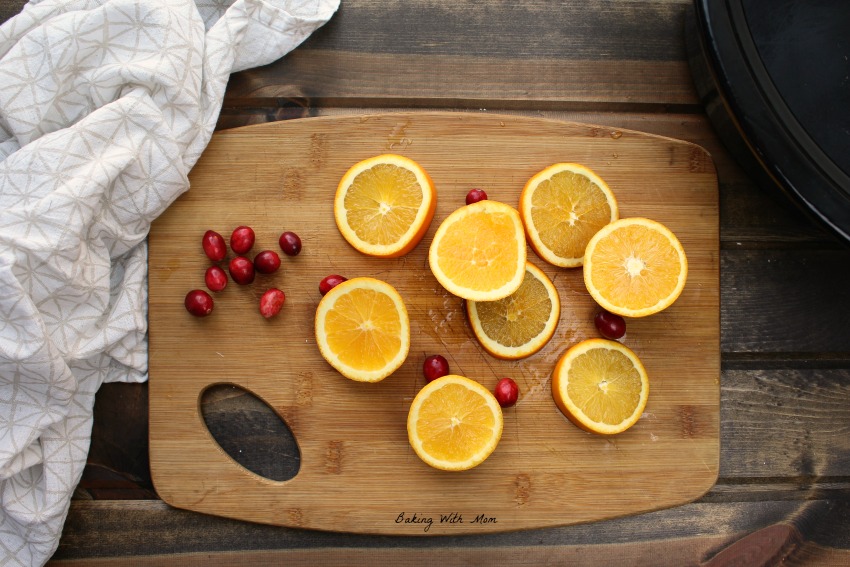 Cut oranges and whole cranberries on a cutting board