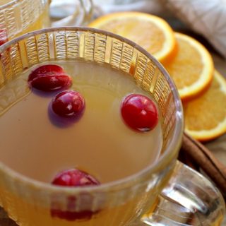 Spiced Apple Cider in clear cups with oranges in background