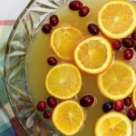 Holiday Orange Juice Punch with orange slices and cranberries in a punch bowl