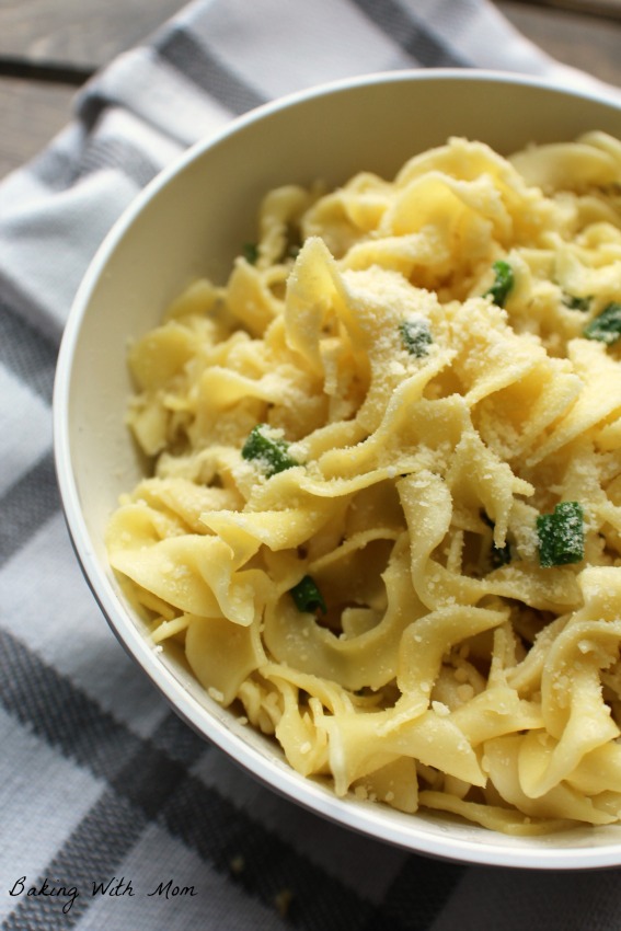 Cheesy Buttered Noodles with chopped green onions in a white bowl