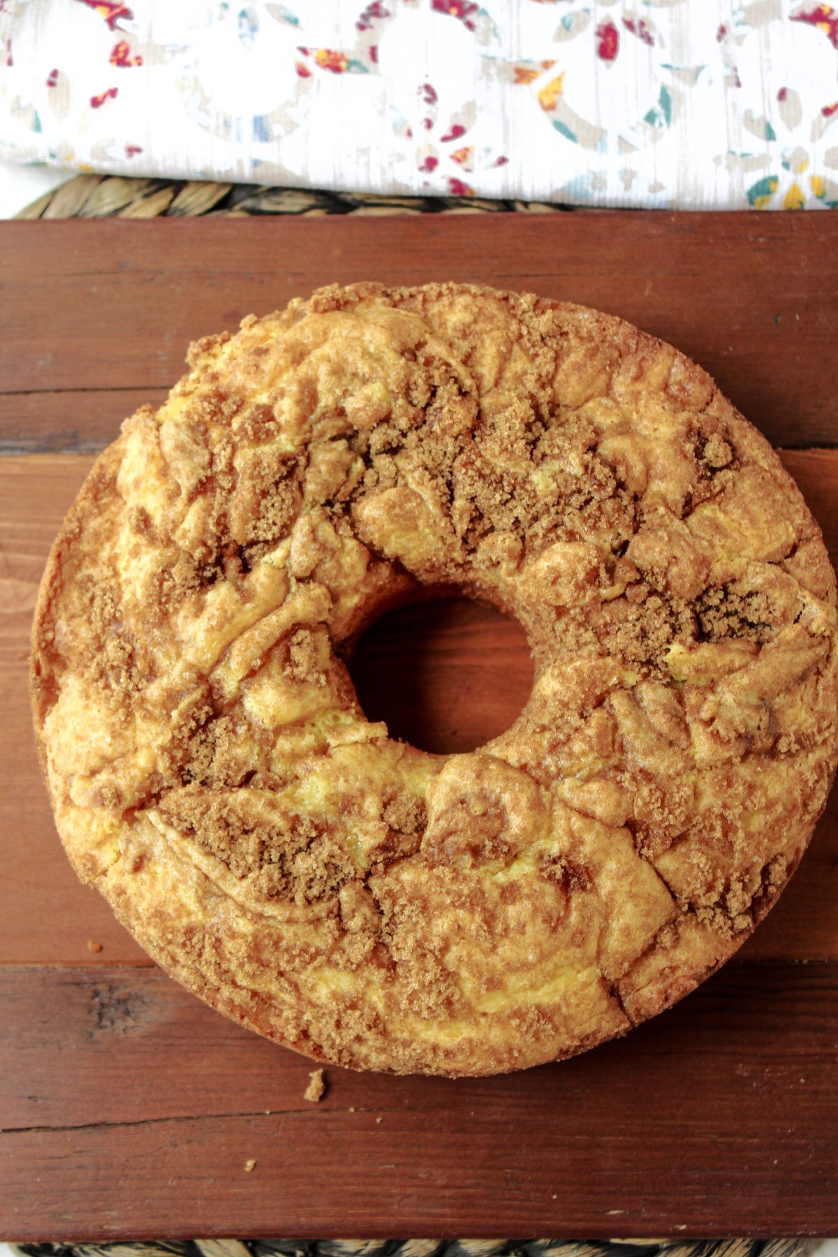 brown sugar coffee cake on a brown board with a towel nearby.