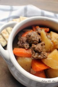Beef stew meat with potatoes, carrots and celery in a white bowl