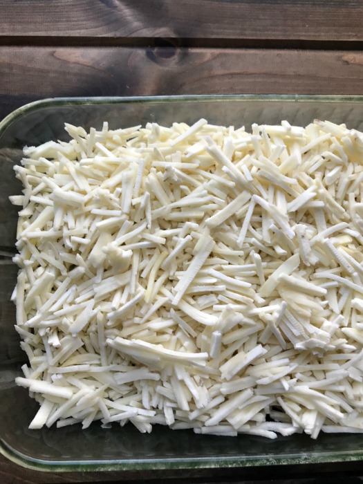 Frozen shredded hashbrowns in a clear baking dish