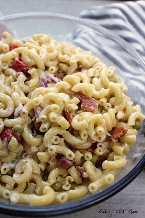 Macaroni salad in a clear bowl with bacon and tomatoes