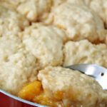 peach dumplings with a spoon in a pan.
