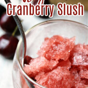 cranberry slush in a clear cup with a spoon.