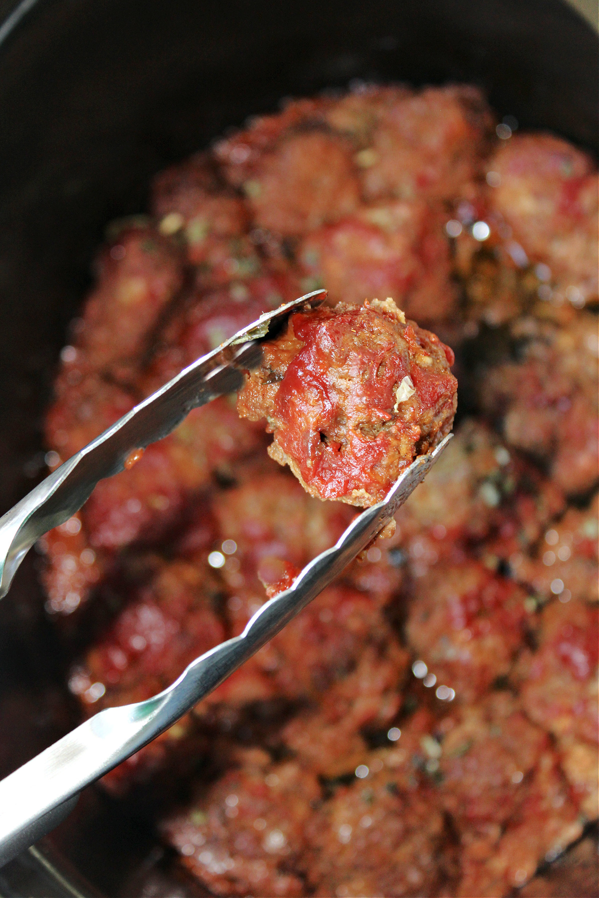 bbq meatballs with tongs.