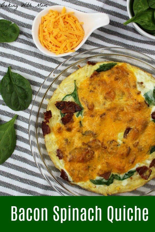 Bacon Spinach Quiche in a clear pie pan with cheese and spinach leaves on the side